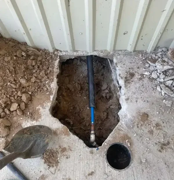 Concrete slab cut open exposing the drain line and cleanout
