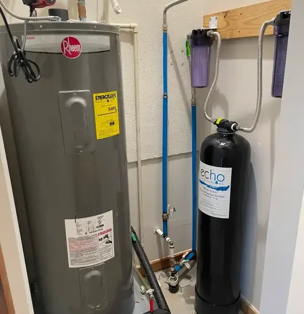 Electric tank water heater beside a whole-house filtration tank