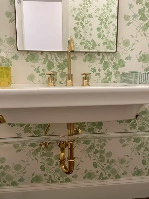 Trough-style sink with brass fittings in a floral powder room
