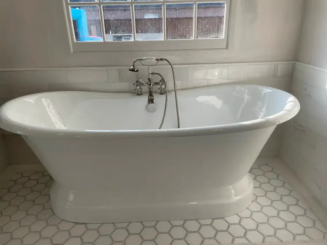 Freestanding soaking tub with floor-mounted filler on hex tile
