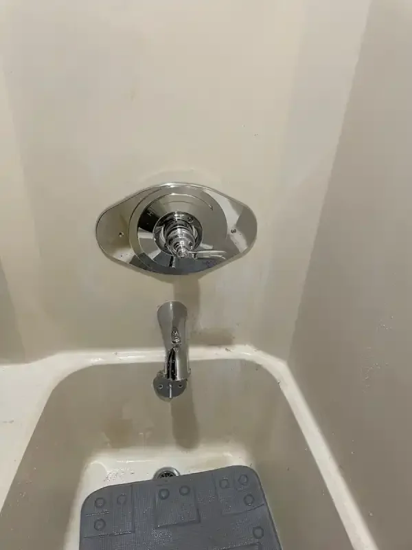Tub spout and valve trim installed in a white alcove tub