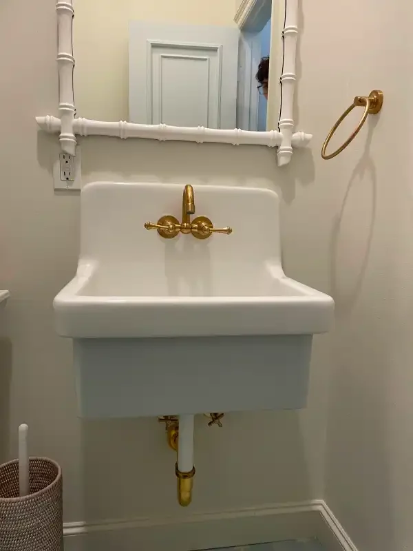 Wall-hung utility sink with exposed brass supply piping