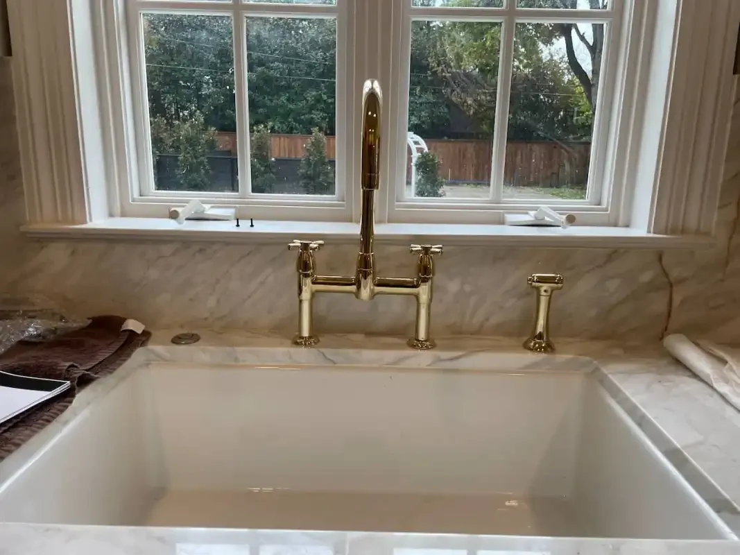 Marble-surround kitchen sink with a brass bridge faucet