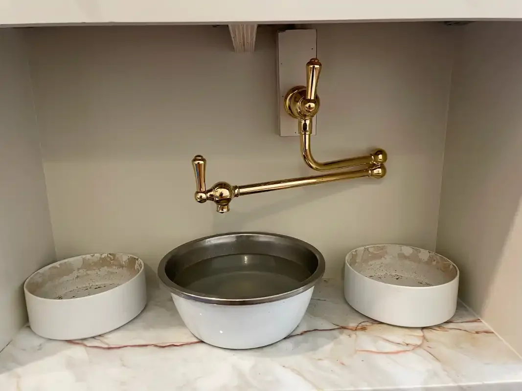Brass pot filler over a marble counter with mixing bowls