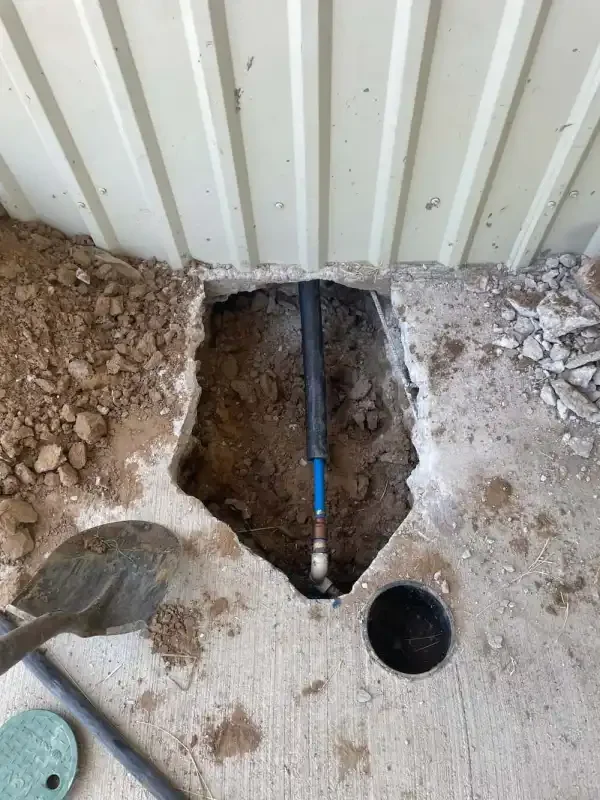 Concrete slab cut open exposing the drain line and cleanout