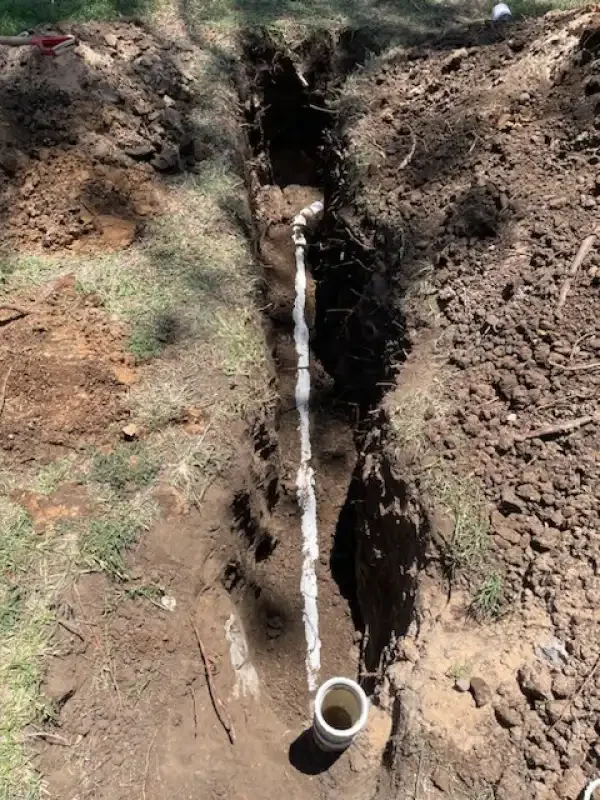 Open trench with new sewer line and cleanout riser