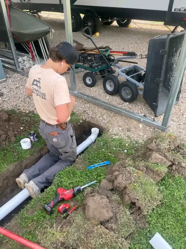 A+ Plumbing tech running a sewer line beside a trailer