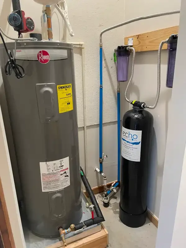 Electric tank water heater beside a whole-house filtration tank