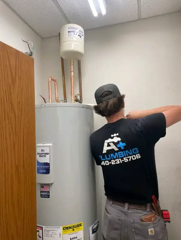 A+ Plumbing tech installing a tank water heater indoors