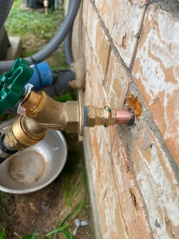 Brass backflow assembly at an exterior brick wall