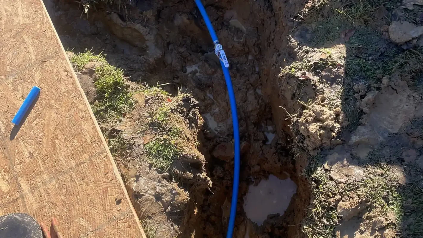 Blue PEX water service line in a trench beside a walkway
