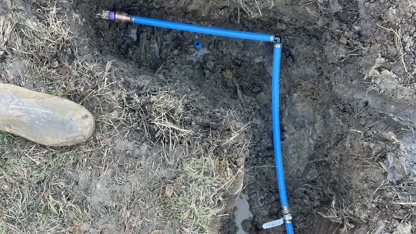 Blue PEX water line run through a shallow trench
